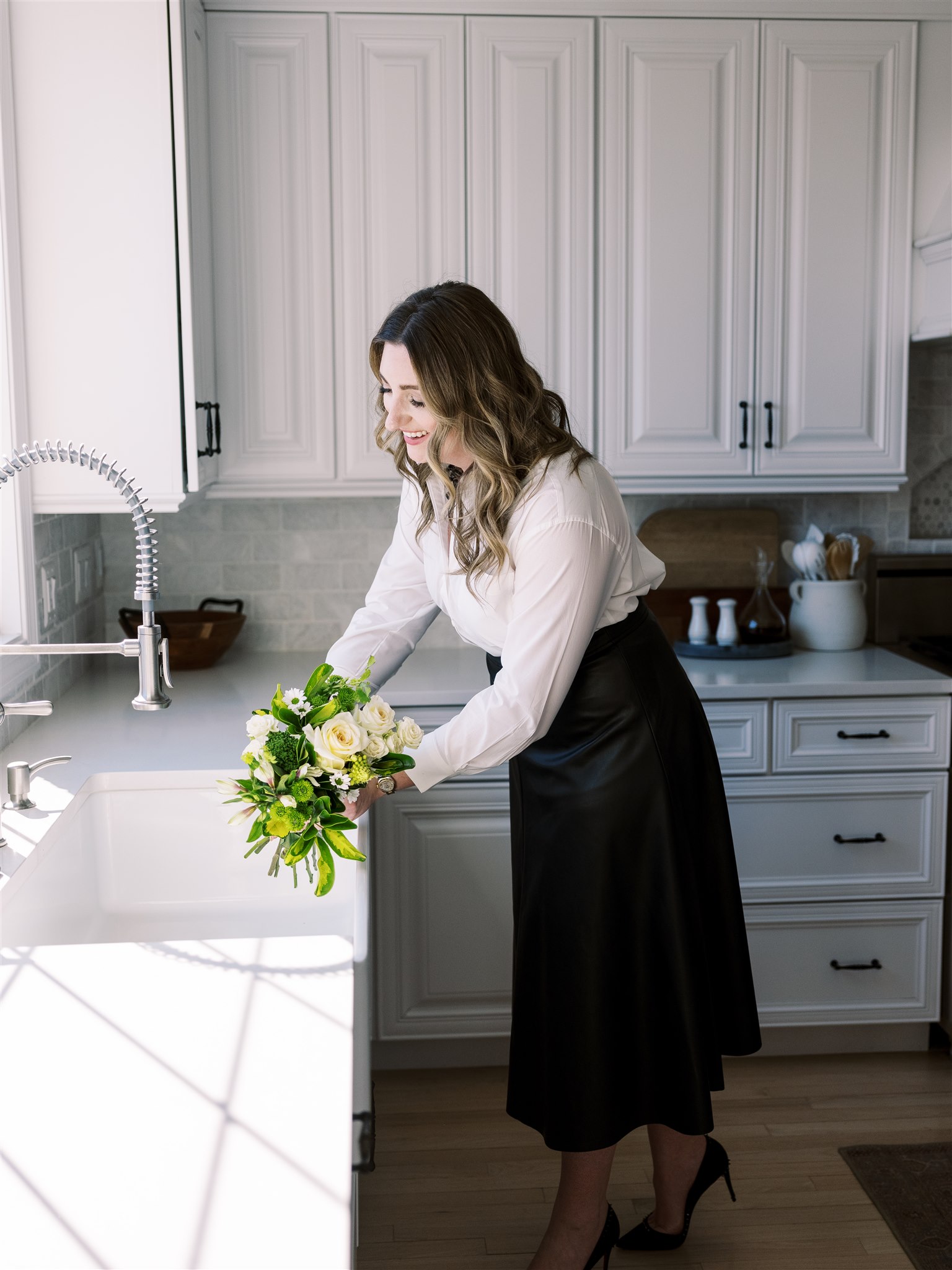 woman with flowers next to sink in white kitchen